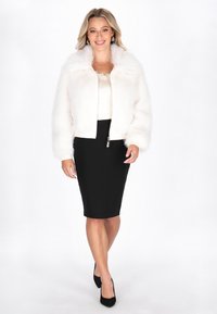 Weiße Kunstpelzjacke mit einem verkürzten Design und einem Schalkragen, kombiniert mit einem schwarzen Bleistiftrock und schwarzen Heels. Glatte Texturen insgesamt.