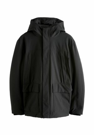 Jachetă izolată neagră, cu glugă, croială largă, buzunare frontale cu clapetă și textură netedă. Design minimalist, fără logo-uri vizibile.