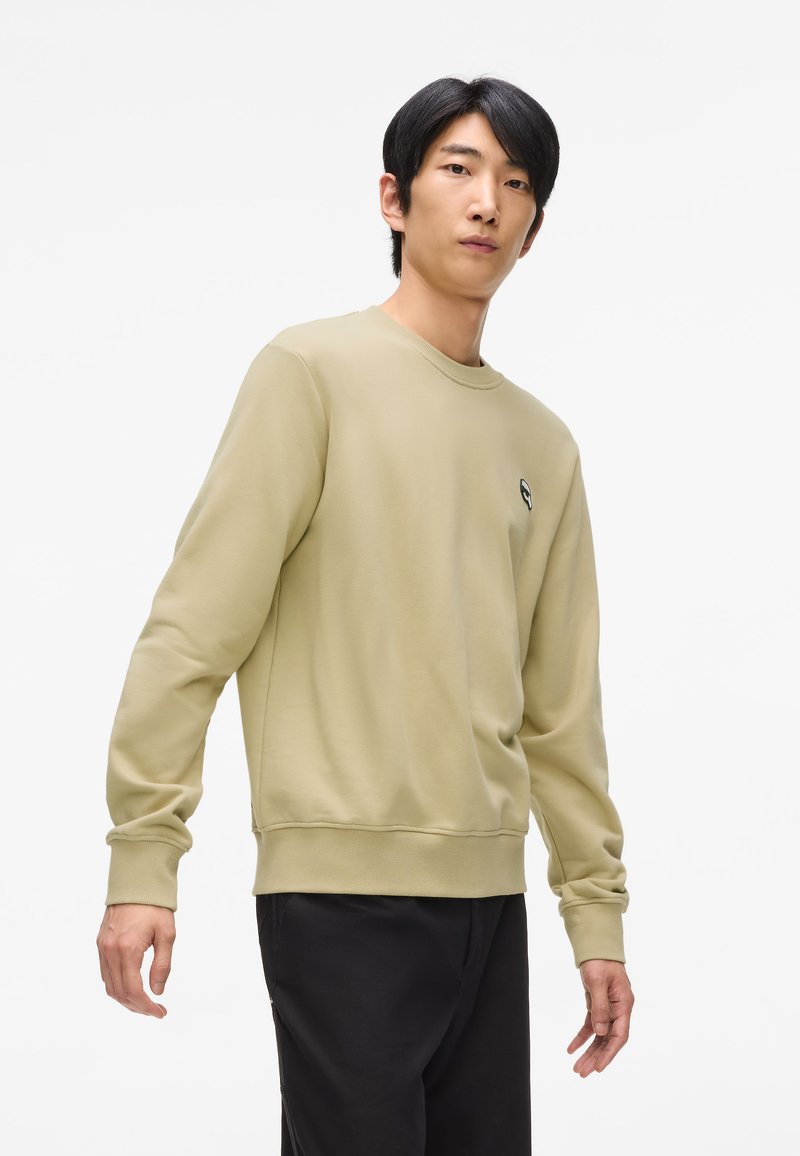 Groene katoenen sweatshirt met ronde halslijn, geribde manchetten en onderrand. Heeft een klein logo op de borst. Draagt het met donkere broek.