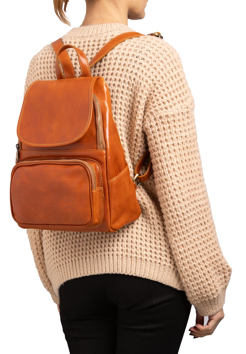 Sac à dos en cuir orange avec une fermeture à rabat, poche zippée à l'avant et bretelles ajustables. Surface texturée et design minimaliste.
