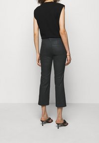 Black sleeveless top paired with dark gray cropped pants. The pants have a fitted design, with two back pockets and a subtle sheen.