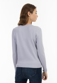 Pulover de culoare lavandă deschisă, cu mâneci lungi, manșete și tiv cu nervuri, textură netedă. Are un decolteu rotund și o siluetă ajustată.