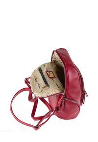 Zaino in pelle rossa con superficie testurizzata, doppie cerniere e spallacci regolabili. L'interno presenta una fodera beige con un motivo a scritta e una tasca con cerniera.