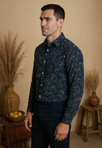 Donkerblauwe overhemden met een bloemmotief in goud, wit en teal. Heeft een klassieke kraag en een getailleerd silhouet. Gecombineerd met donkere broeken.