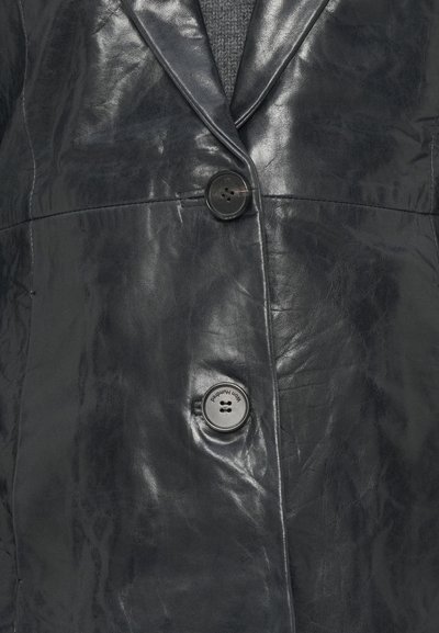 Czarna skórzana marynarka z klapą z nacięciem, dwoma guzikami i pomarszczoną fakturą. Materiał jest błyszczący i wypolerowany.