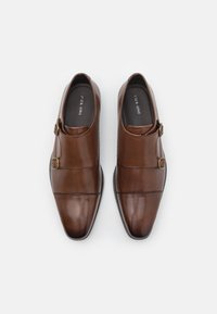 Zapatos de cuero marrón con un diseño elegante, punta afilada y detalle decorativo de hebilla. Textura suave y mínimos acentos de costura.