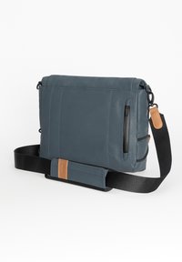 Graue Leder-Umhängetasche mit einem Reißverschlussfach, verstellbarem schwarzen Tragegurt und einem braunen Akzentpatch. Hat klare Linien und eine rechteckige Form.