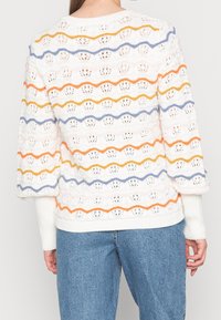 Weißer Strickpullover mit Wellenmuster in orange, blau und pink gestreift, mit Durchbrüchen und gerippten Bündchen sowie Saum.