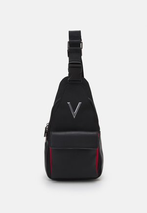 Schwarze Umhängetasche mit verstellbarem Riemen, Frontreißverschlussfach, roten Seitenelementen und einem metallischen "V"-Logo auf der oberen Vorderseite.