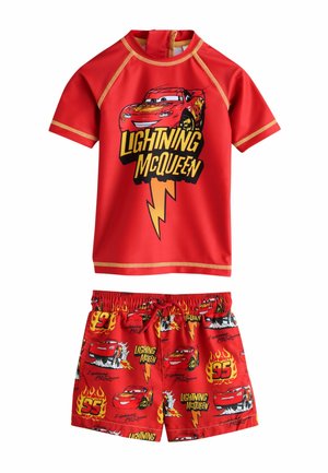 Rød Lightning McQueen badetøjssæt med en kortærmet top med lyn-motiv og mønstrede shorts med biler og flammer.
