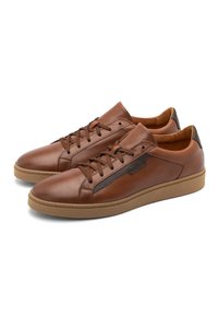 Brązowe skórzane sneakersy z płaskimi sznurowadłami, teksturowaną boczną wkładką i tanowym gumowym podłożem. Dodatkowe detale to kolorowy pasek na języku.