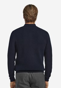 Marinblå texturerad stickad tröja med krage, med långa ärmar och ribbade muddar, kompletterad med en rak fåll.