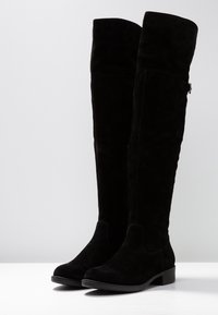 Stivali neri in suede al ginocchio con punta tonda, tacco basso a blocco e cerniera laterale. Texture liscia con hardware e dettagli di cucitura minimi.