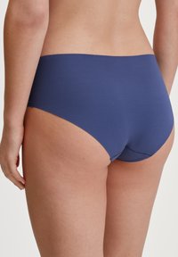 Le mutande bikini in cotone blu navy presentano una texture liscia, vita bassa e cuciture minime. Il design è semplice, senza motivi o accenti aggiuntivi.