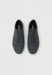 Pelēkas kurpes ar gludu ādas ārpusi, apaļām šņorēm, baltu zoli un smalku logotipu zolē.