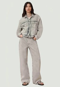 Gray denim jacket with front pockets, worn over matching gray wide-leg pants. Features a relaxed fit and subtle distressed texture.