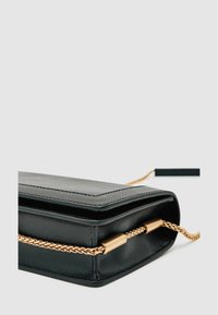 Fekete bőr cluth táska egyszerű téglalap alakban, arany láncos pánttal és sima, elegáns felülettel.