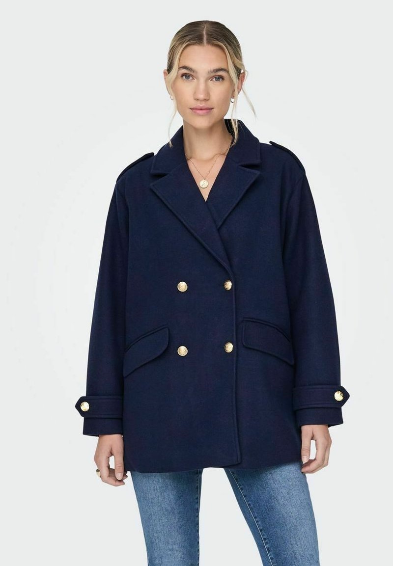 Manteau croisé bleu marine avec boutons dorés, grandes poches latérales et épaulettes ; fabriqué en tissu texturé.