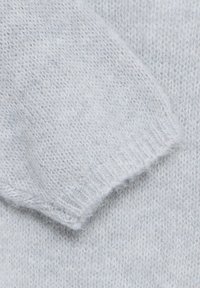 Tissu tricoté gris clair doux avec un détail à bord côtelé, présentant une texture duveteuse et un motif serré.