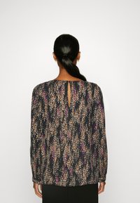 Blusa a maniche lunghe nera con motivo astratto multicolore. Presenta un dettaglio sul retro a occhiello e un tessuto testurizzato.