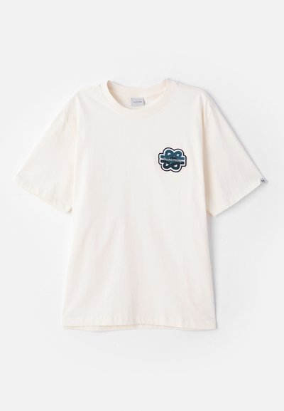 Krēmkrāsas kokvilnas t-kreklu ar īsām piedurknēm, ar tumši zilu izšūtu logotipu kreisajā krūšu daļā. Gluda tekstūra.