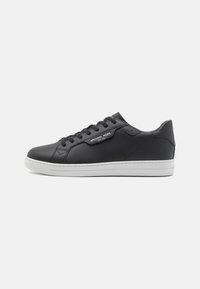 Black leather sneaker with a smooth finish, white rubber sole, round toe, six eyelet lacing system, and branded label on the side.