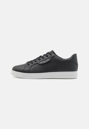 Black leather sneaker with a smooth finish, white rubber sole, round toe, six eyelet lacing system, and branded label on the side.