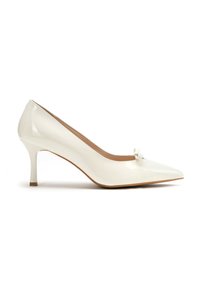 Décolleté bianco in vernice con punta affilata, tacco basso e piccolo fiocco decorativo sulla tomaia. Texture liscia e lucida con un design elegante.