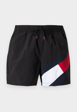 Schwarze Badeshorts mit elastischem Bund, schwarzem Kordelzug und diagonalem Farbblock in Rot, Weiß und Marineblau am rechten Bein.
