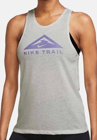Hellgraues Nike Trail Tanktop mit atmungsaktivem Mesh-Gewebe, lila Logo und Berggrafik, ärmelloses Design und abgerundetem Ausschnitt.