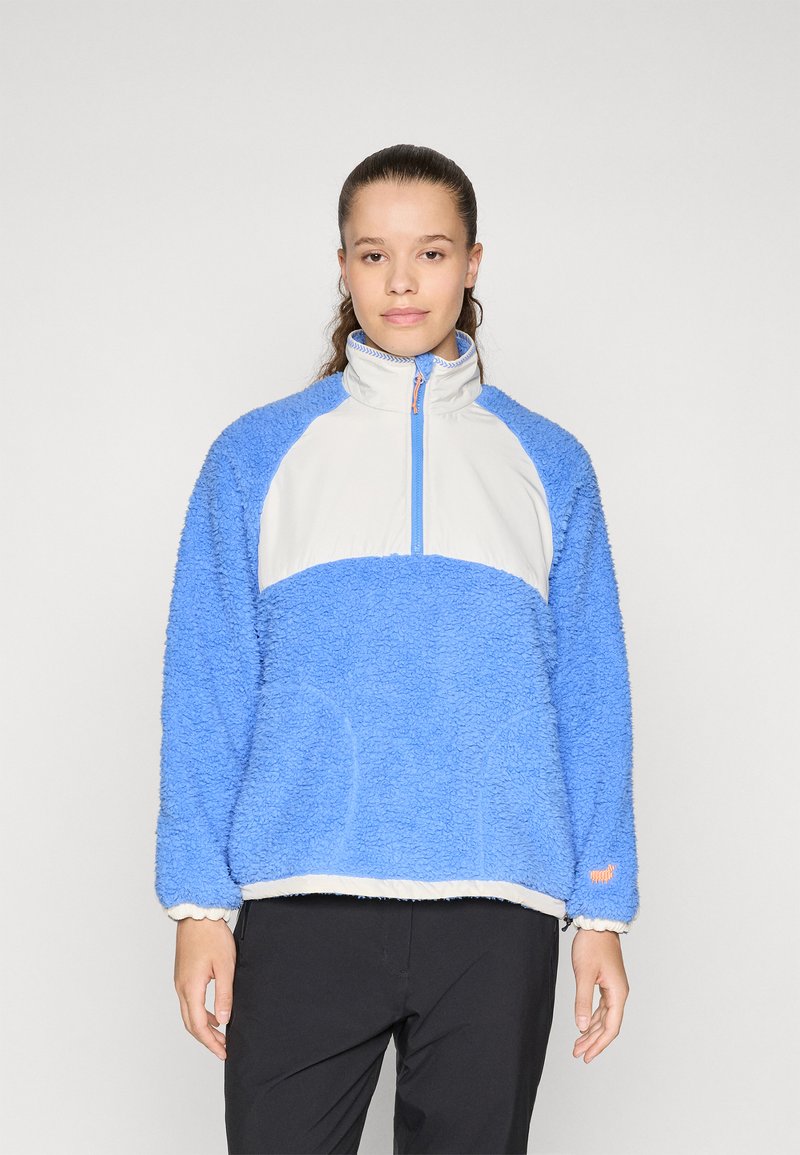 Blå fleece-pullover med en hvit frontpanel, høy krage og glidelås. Har en myk tekstur og oransje detaljer på kanten.