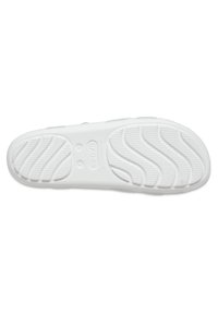 Vit gummisula med en vågmönster och texturerat grepp. Kännbara varumärkeslogotyper i cirklar finns nära mitten och hälen.