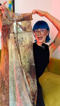 Sheer dress with a multi-colored abstract pattern in earthy tones. Features buttons and a decorative ring on the neckline. Long and flowing design.