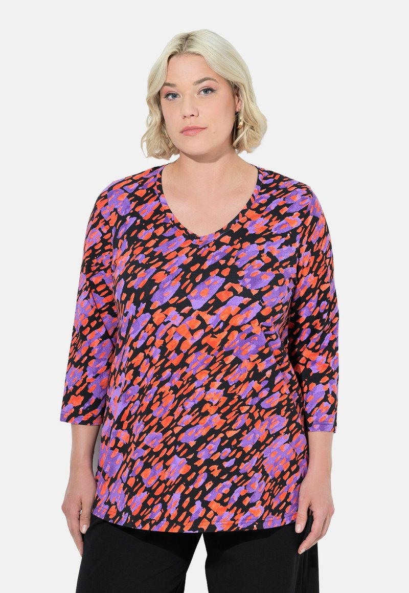 Pitkähihaisen tunikan musta kangas, jossa on eläväinen violetti ja oranssi abstrakti kuvio, syvällä V-aukolla.