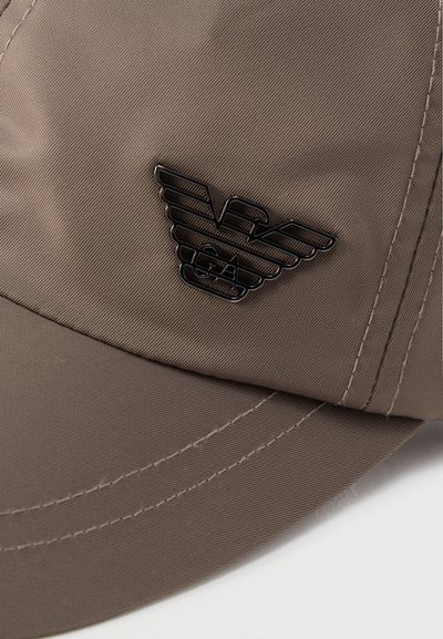 Καφέ-γκρι καπέλο μπέιζμπολ με μαύρο μεταλλικό λογότυπο που απεικονίζει στυλιζαρισμένα φτερά και τα γράμματα "EA" στο μπροστινό πάνελ.