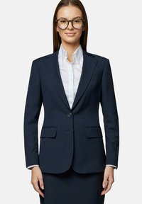 Granatowa marynarka o dopasowanym kroju, z jednolitym zapięciem na guzik, dwoma przednimi kieszeniami i gładką fakturą, zestawiona z białą koszulą z kołnierzykiem.