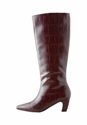 Burgundy nahka saappaat, jotka ulottuvat polven ylle, kiiltävällä krokotiilitekstuuri, terävä kärki ja kohtalainen lohko korko.