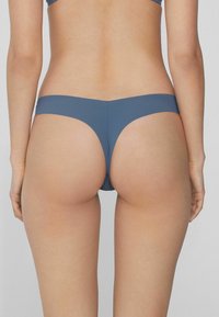 Blaue Bikinihöschen aus Stretchstoff, mit einem niedrigen Schnitt, minimaler Bedeckung und glatter Textur.