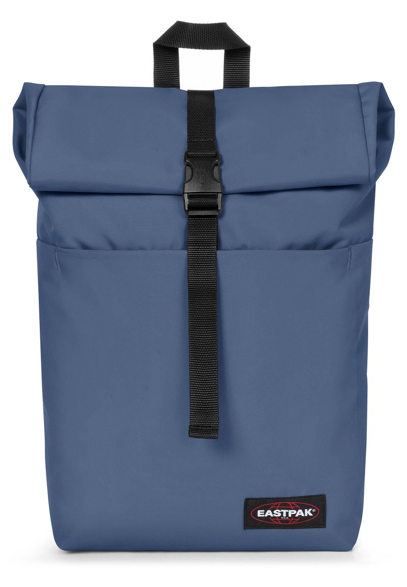 Zaino roll-top blu con finitura testurizzata, dotato di una tracolla nera e chiusura a fibbia, e un patch con il logo del marchio Eastpak.
