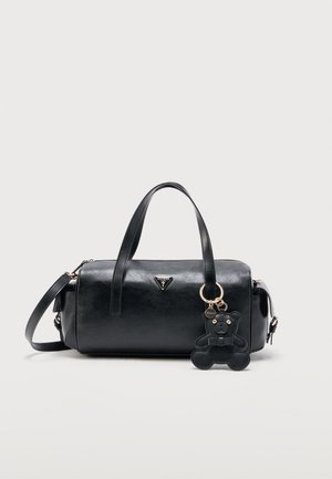 Sac à main cylindrique en cuir noir avec double poignée, bandoulière amovible, logo métallique à l'avant et un porte-clés en forme d’ours noir.