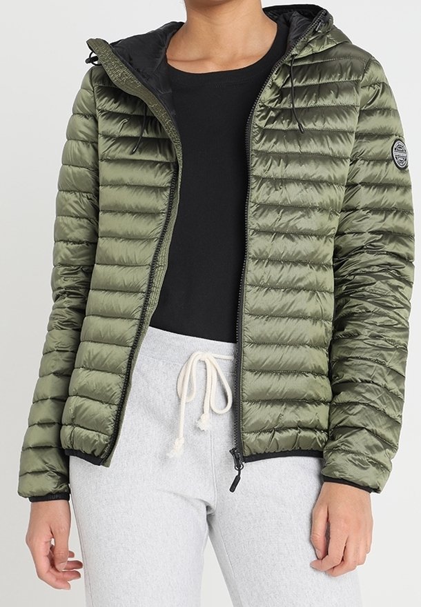 Olijfgroen pufferjack met horizontaal geruit patroon, ritssluiting aan de voorkant, verstelbare capuchon en zwarte voering. Gecombineerd met een zwarte top en grijze broek.