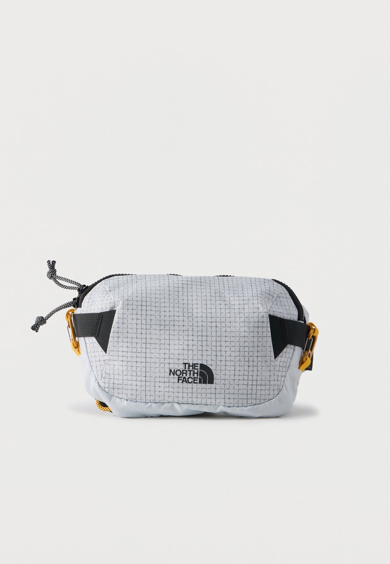 Συμπαγής γκρι τσάντα ώμου με μαύρο γεωμετρικό μοτίβο, μαύρους ρυθμιζόμενους ιμάντες, κίτρινες αγκράφες και λογότυπο "The North Face" στο μπροστινό μέρος.