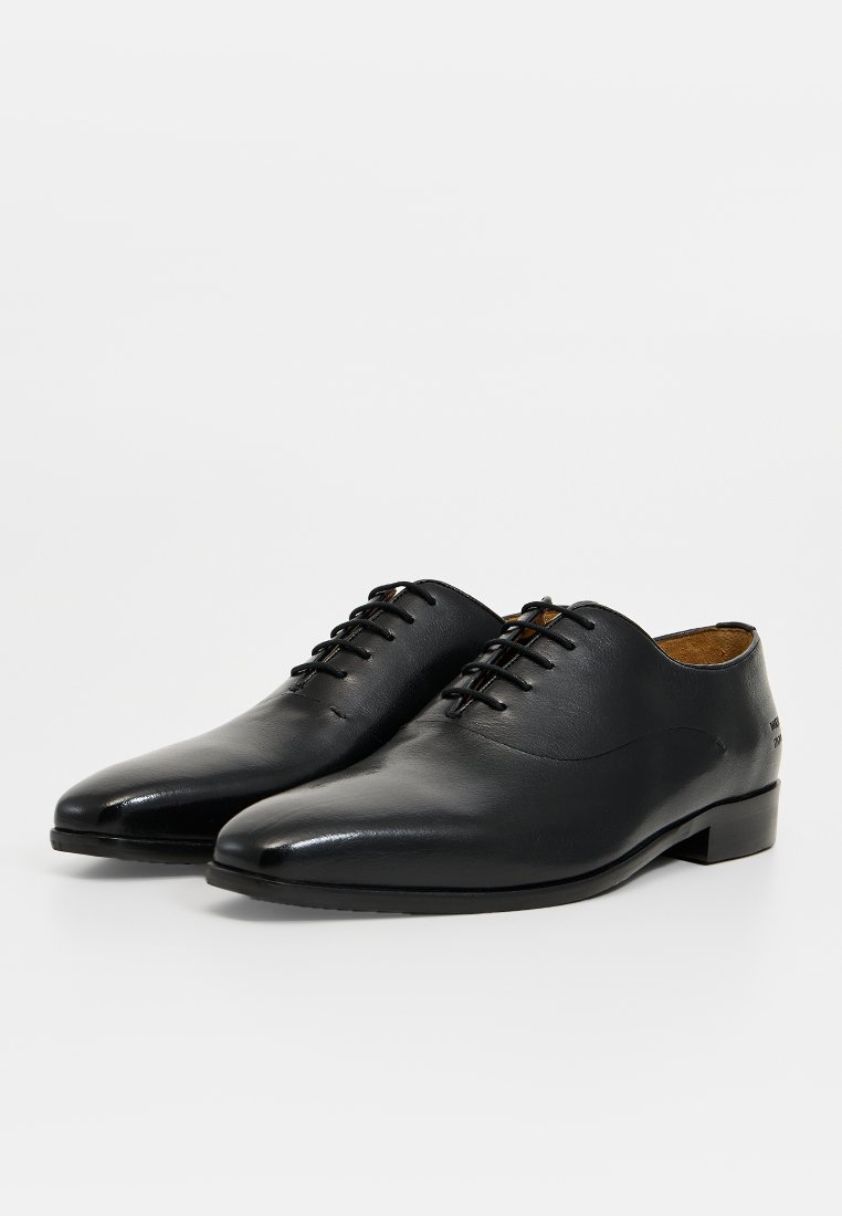 Chaussures habillées en cuir noir avec un embout pointu élégant, un laçage à l'avant et une texture lisse. Elles présentent un talon bas et un design minimaliste.