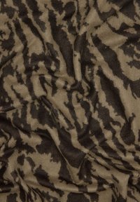 Tkanina w wzór zwierzęcy w odcieniach tan i ciemnego brązu, charakteryzująca się miękką, teksturowaną powierzchnią, elastycznym układem i falistym wzorem.