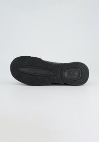 Black rubber shoe sole with a textured surface, featuring deep grooves for traction and an oval central design detail.