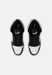 Czarno-białe buty sportowe z perforowaną białą częścią palców, czarnymi sznurówkami, wyściełanym czarnym kołnierzem i wyraźnym logo Pumy na czarnej języku.