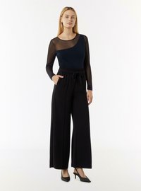 Zwarte wijde broeken met een trekkoord in de taille, gecombineerd met een marineblauw top met doorzichtige gestreepte lange mouwen en een ronde halslijn.