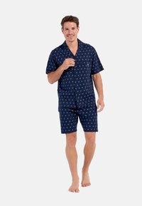 Pyjama à manches courtes bleu marine avec un motif d'étoiles, comprenant une chemise à boutons et un short assorti, fabriqué en tissu lisse.
