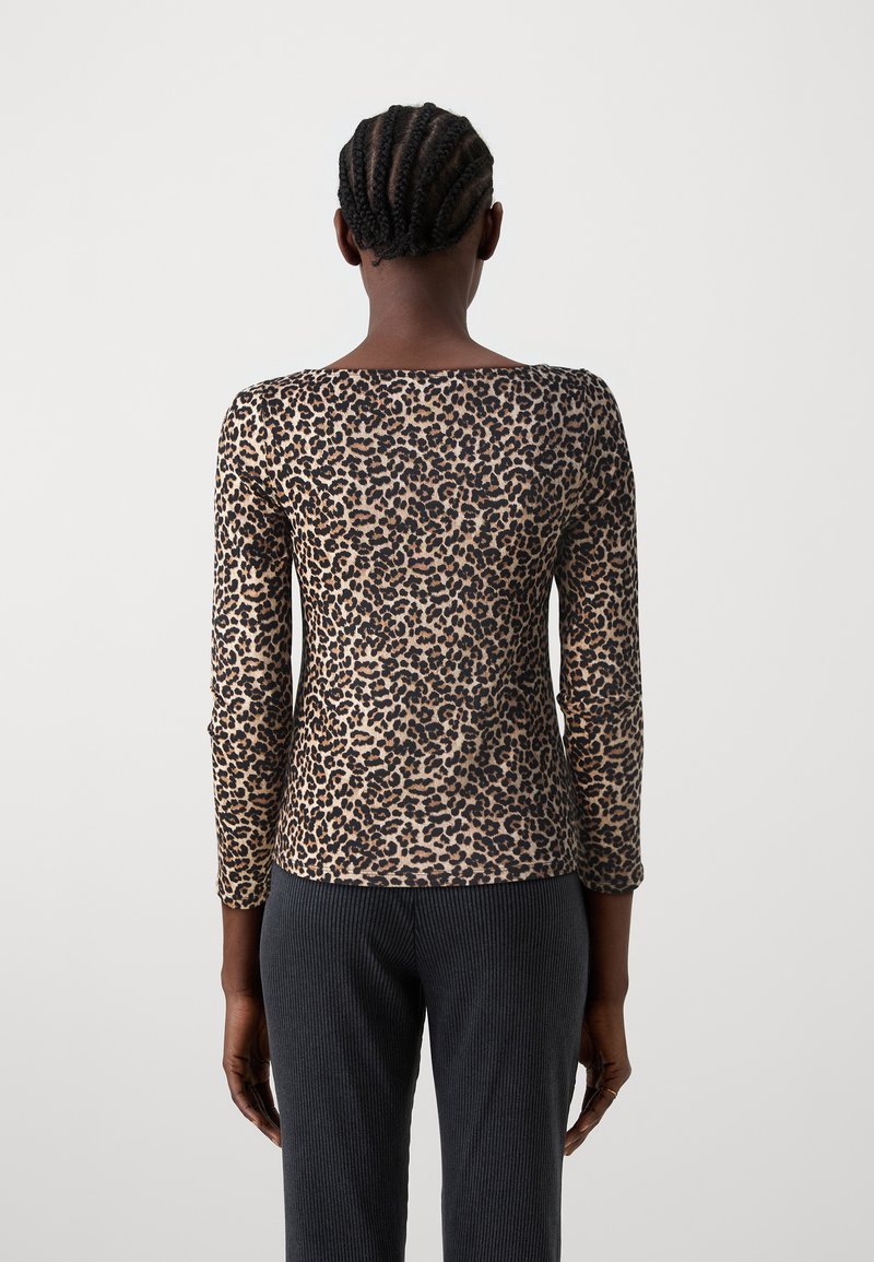 Beige und braunes Langarm-Oberteil mit Leopardenmuster aus leichtem Stoff, mit Rundhalsausschnitt und tailliertem Schnitt. Strukturierte Ripp-Hosen sind sichtbar.