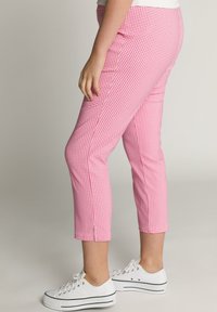 Růžové a bílé kostkované zkrácené kalhoty s úzkým střihem. Mají boční rozparek na lemu. Spárovány s bílými teniskami.